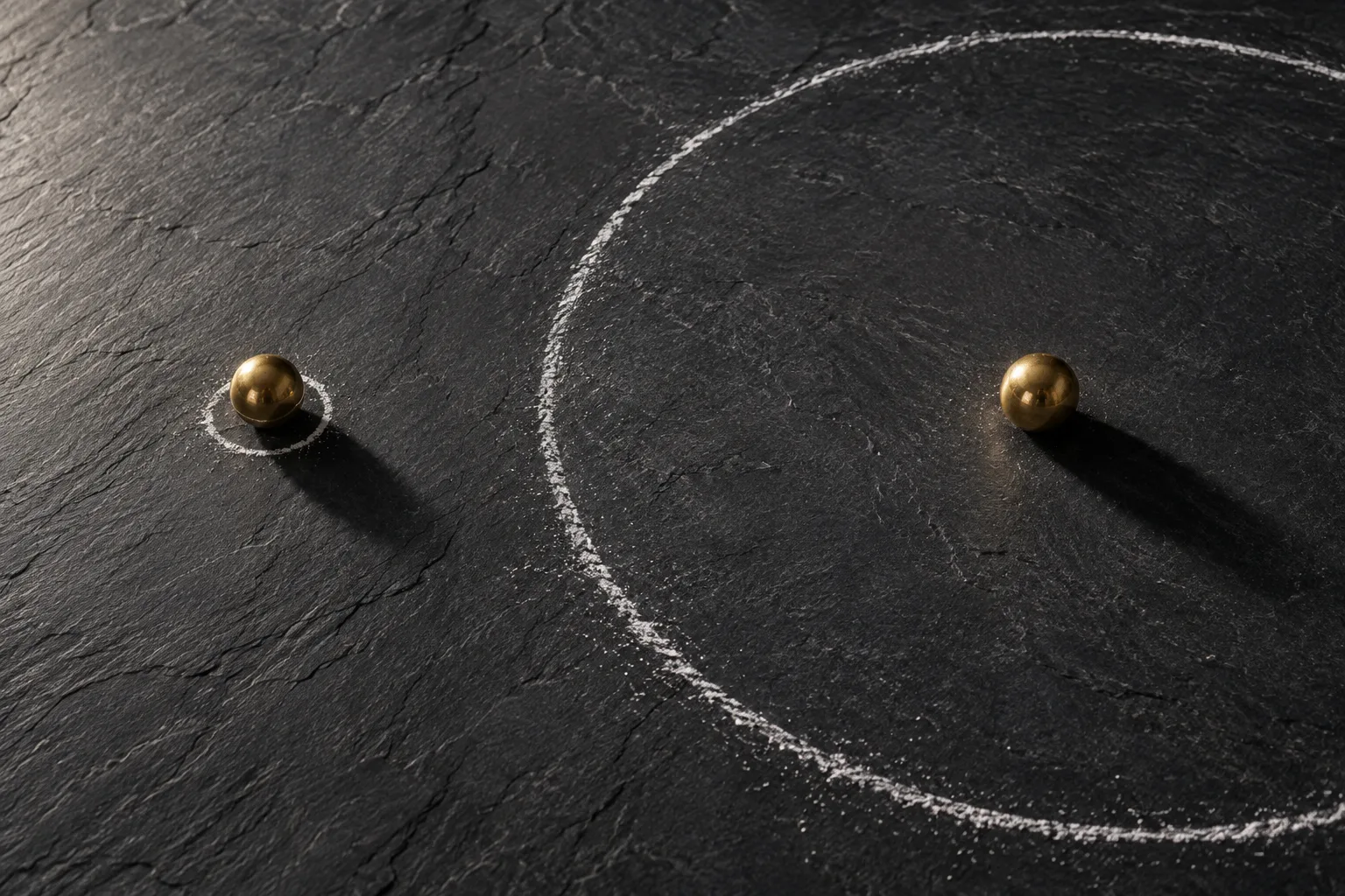 A brass sphere shown inside a tiny chalk circle and again at the center of a vast chalk circle, contrasting narrow and broad boundaries